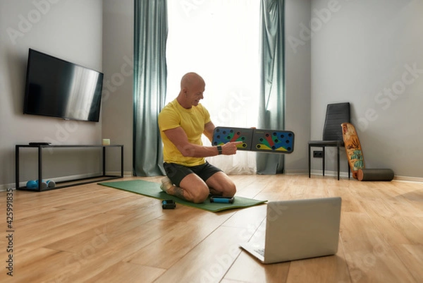 Obraz Man demonstrating push up training system in laptop