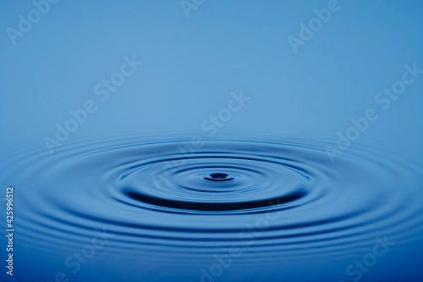 Obraz Closeup Water drop or splash falling on the surface of the water and beautiful circular wave ripple, water concept, with blue background