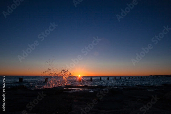 Fototapeta Sunrise shining at Dawn over Lake Michigan in Downtown Chicago while a Wave splashes up