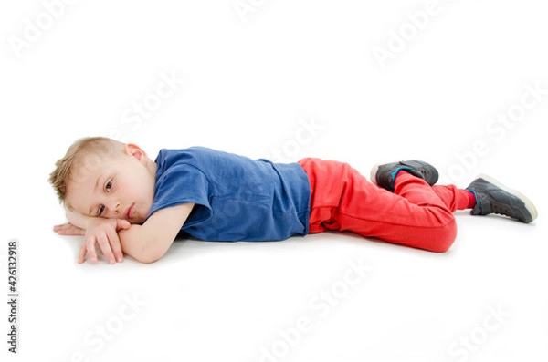 Obraz Little boy feels annoyed grumpy lying on the floor. Isolated on white background
