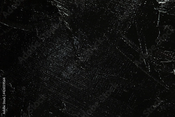 Fototapeta Dark creative background - rough linen canvas unevenly covered with black primer, reflections of light. Toning, blurring, selective focus.