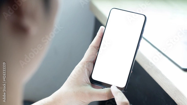 Fototapeta Hand holding and using smartphone with white blank on screen.