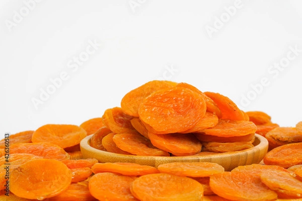 Obraz Dried apricots on white background. Naturally dried apricot on white.  Sun dried fruits in wooden bowl. Product for sale. Copy space. 