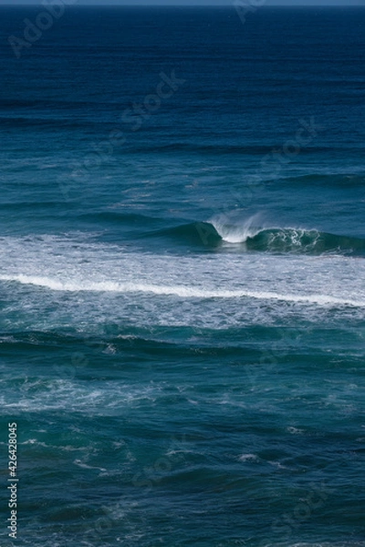 Fototapeta Big blue wave breaks in a dark blue ocean