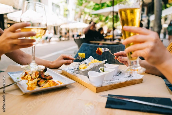 Obraz a glass of beer and wine on a table with utensils two girls have dinner together in a restaurant on the terrace in summer