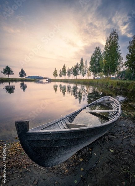 Fototapeta Old rowboat with calm lake and mood sunset at autumn evening in Finland