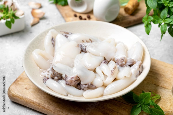 Obraz Raw cuttlefish in a ceramic plate on the kitchen table. Lots of peeled squid in a bowl on a light background. The concept of cooking shellfish