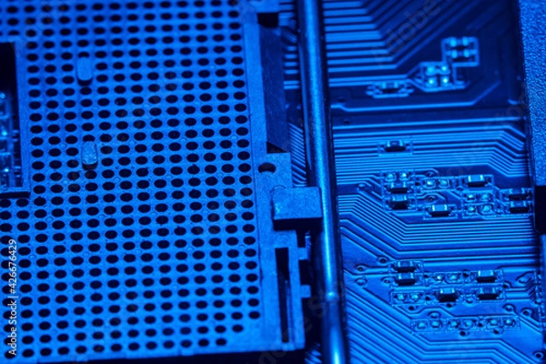 Fototapeta High tech dark background with elements of a computer motherboard in soft focus under high magnification. A slot for a processor with a lever for locking onto the home computer board.
