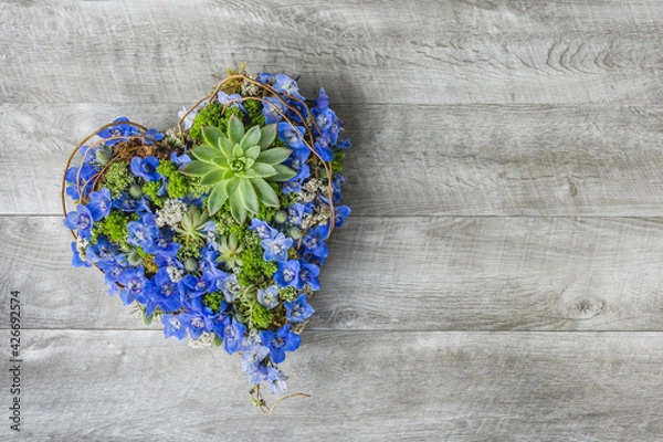 Fototapeta Heart shape of blue flowers on a grey wooden background - Wood Table flat lay - Sympathy flowers - Romantic flowers