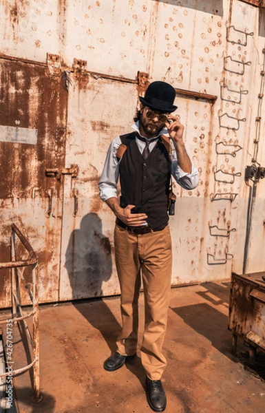 Fototapeta Steampunk. A hero on a river barge surrounded by steel mechanisms. A man with a weapon.