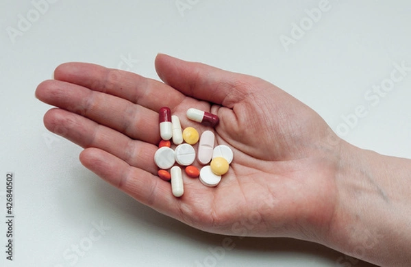 Fototapeta hand with syringe and medical mask and capsules on white background