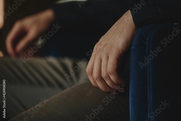 Fototapeta The man sits next to the wall looking forward, the room is dim