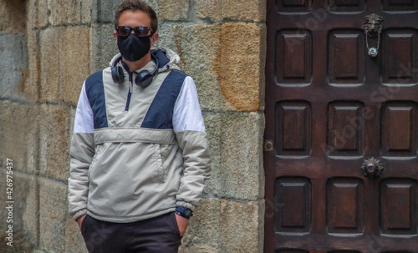 Obraz man through the monumental streets with medical mask and headphones in the new normal