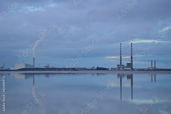 Fototapeta Dublin Waste to Energy (Covanta Plant), Poolbeg CCGT and Pigeon House Power Station view from Blackrock Beach, Dublin, Ireland. Beautiful evening view with reflection in the water