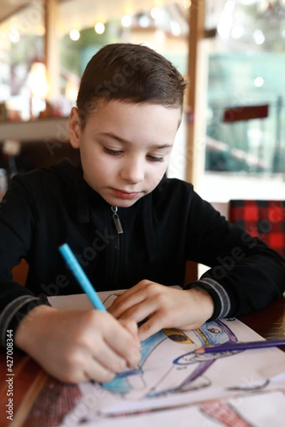 Fototapeta Child drawing with pencils in restaurant