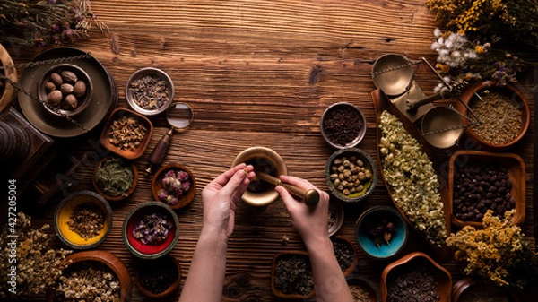 Fototapeta Natural medicine background. Preparation of herbs composition. Assorted dry herbs in bowls and brass mortar on rustic wooden table.
