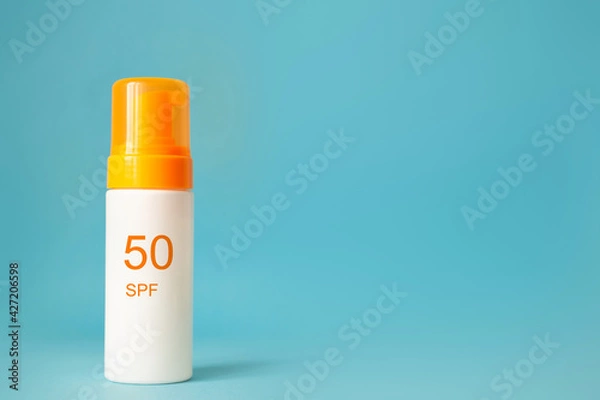 Obraz Sunscreen bottle with spf 50 cream or lotion on the aqua blue background with copy space. Sun protection, summer skin moisturizer