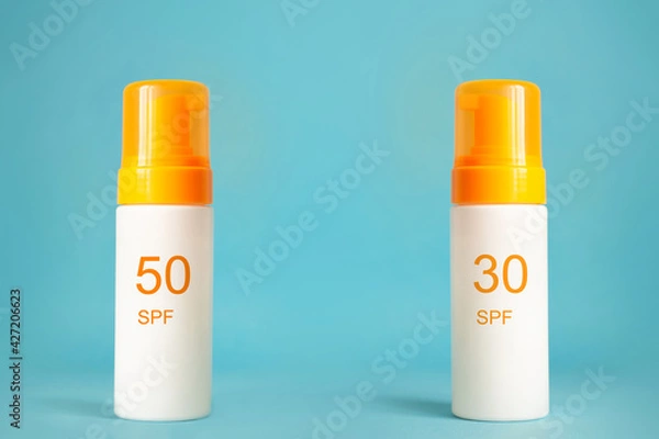 Obraz Sunscreen bottles with spf 30 and 50 cream or lotion on the aqua blue background. Sun protection, summer skin moisturizer choosing