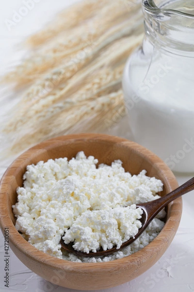 Obraz Cottage cheese  and wooden spoon on white background.