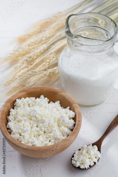 Obraz Cottage cheese  with milk and wooden spoon on white background...