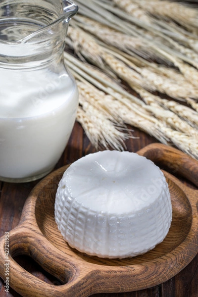 Obraz Round cottage cheese in a bowl with milk on a wooden table.