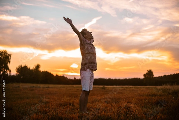 Fototapeta A man in the forest runs on the field, a happy man rejoices in freedom and tranquility. The guy in the field.