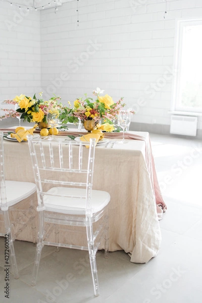 Fototapeta serving on a lemon-colored table. Transparent chairs, rectangular table in a white hall