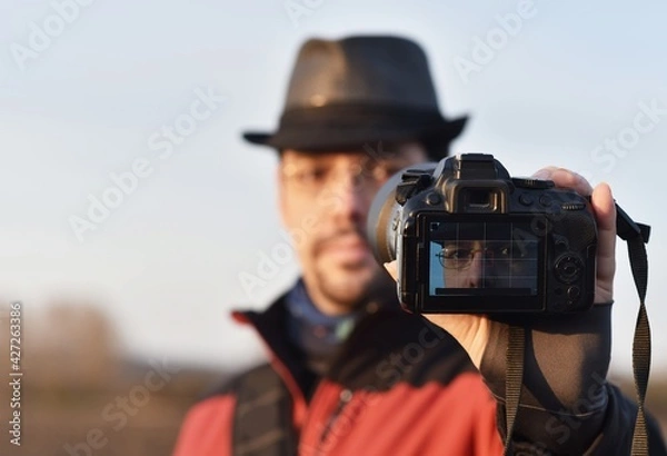 Fototapeta man takes a selfie photo on a dslr camera