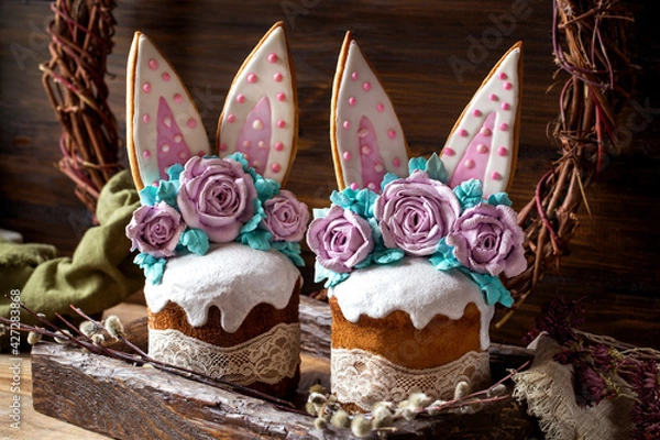 Fototapeta easter cake with rabbit ears made of gingerbread and meringue roses on a dark background