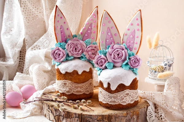 Fototapeta easter cake decorated with rabbit ears and roses meringue flowers on a light background on a wooden saw and willow branches