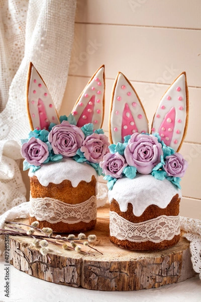 Fototapeta easter cake decorated with rabbit ears and roses meringue flowers on a light background on a wooden saw and willow branches