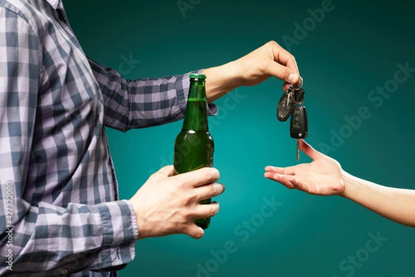 Fototapeta  A man with bottle beer giving a car key to someone for driving the car.Do not drink and drive! Drunk driving. Drink and auto keys.