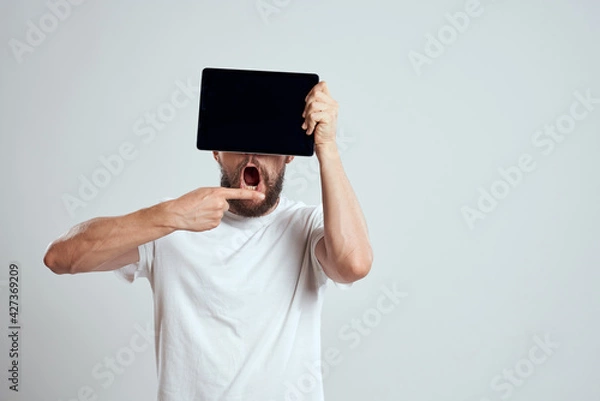 Fototapeta A bearded man in a white t-shirt a tablet in the hands of a professional manager communication technology