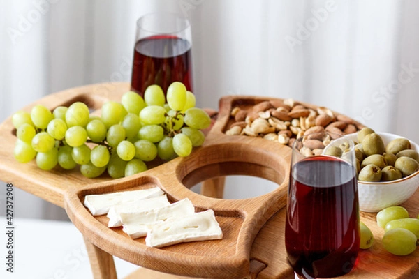 Obraz Serving wooden table for wine, glasses and snacks. Handmade segmented Portion wooden table. Grapes, cheese, wine and nuts.  