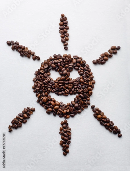 Fototapeta Sunny smile shape made of dark roasted coffee beans on white aquarelle paper background with shadows