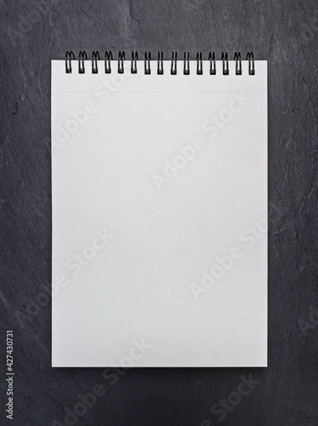Obraz Mockup of open empty blank page of white spiral notepad on black stone background. Copy space for your text. Top view