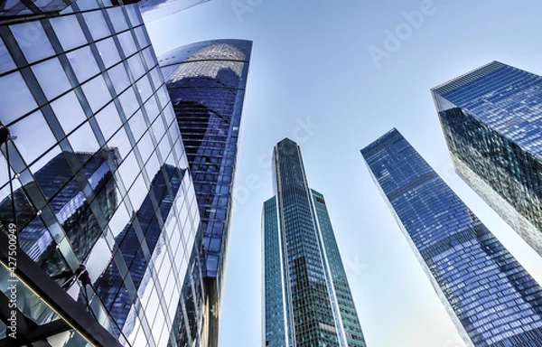 Obraz Spiky skyscrapers of glass, staring up into the blue sky. The image is taken from a low angle.