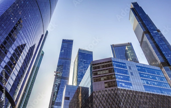 Obraz Modern silhouettes of glass skyscrapers of the city business center with a cloudless, slightly blue sky.