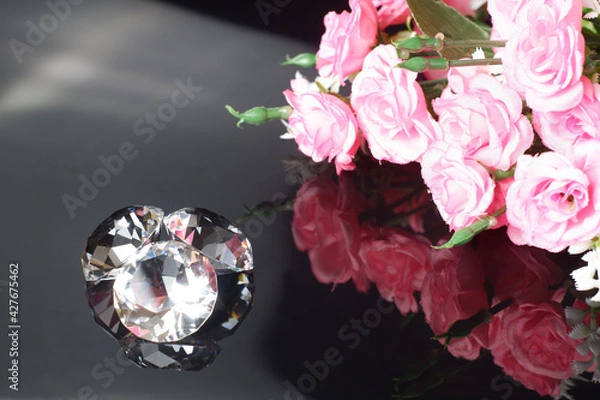 Fototapeta Three excellent diamonds of the first water and bouquet of pink roses with reflection on black mirror background close up view. Jewelry diamonds sale, invitation, action, discount banner template