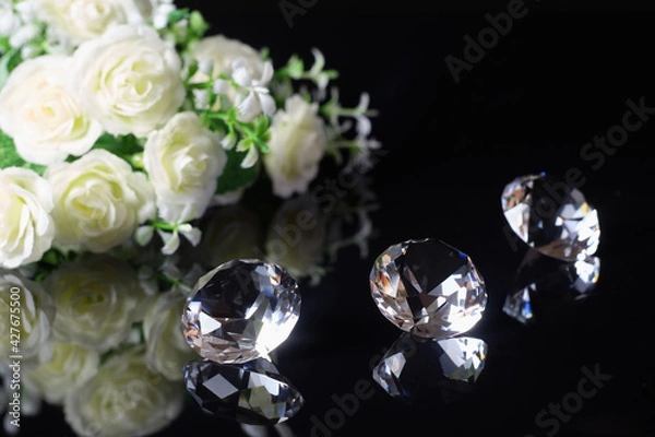 Fototapeta Three excellent diamonds of the first water and bouquet of white roses with reflection on black mirror background close up view. Jewelry diamonds sale, invitation, discount poster template