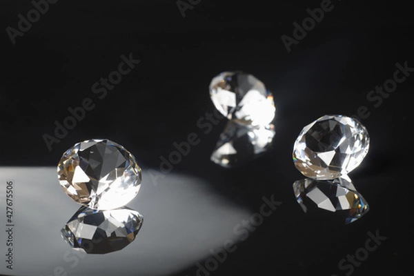 Fototapeta Three excellent pure diamonds with reflection on black mirror background close up view selective focus. Jewelry diamonds sale, invitation, action, discount banner, poster, card template