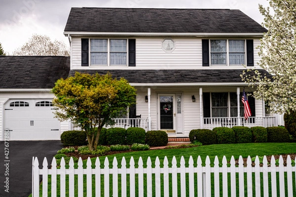 Obraz white colonial house with white picket fence and American flag