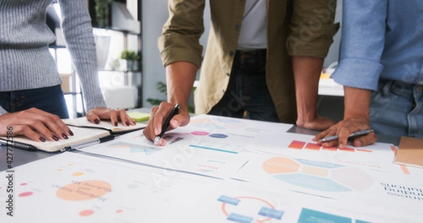 Fototapeta Young Asian business financial team work together in project brainstorm meeting. Cooperate teamwork, strategy planning, small business startup company, or office coworker collaborate concept