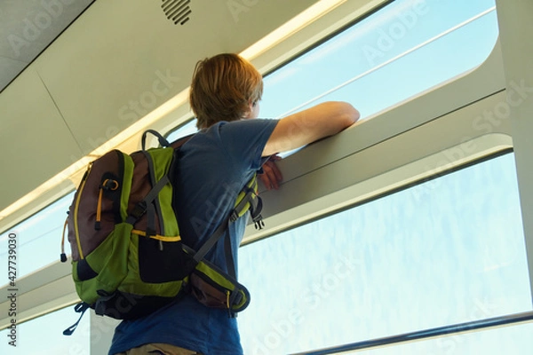 Obraz man with a backpack riding by train. traveler on the road looking out the window.