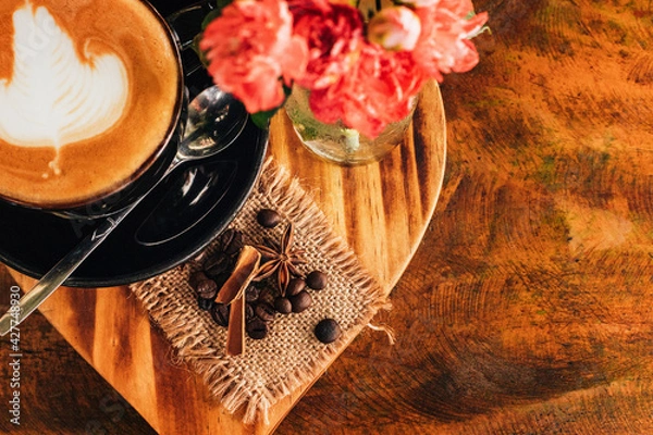 Obraz cappuccino in a black cup. Flowers on the table