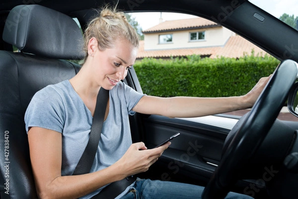 Fototapeta woman texting message by smart phone while on a car