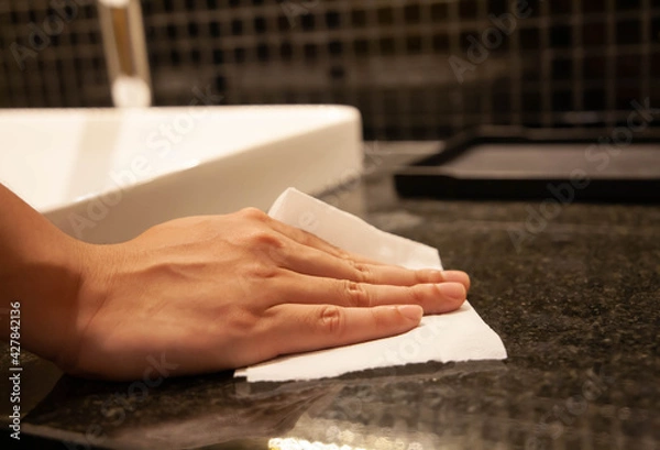 Obraz Cleaning surface. Closeup of hand using paper wipe cleaning dark stone marble surface. Concept of disinfection surface to prevent coronavirus infection, get rid of dust, germs. Selective focus.