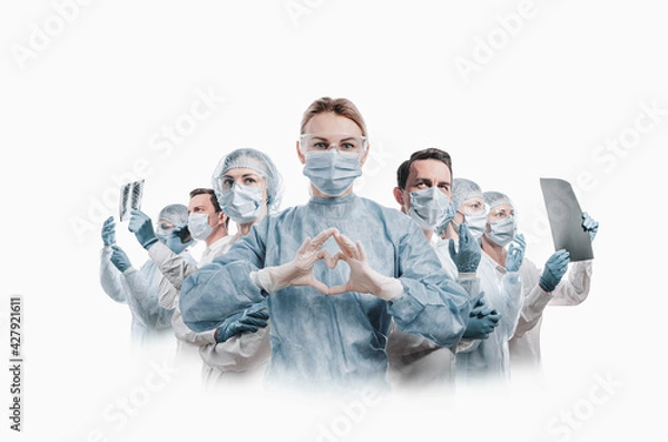 Fototapeta medical workers heroes. a nurse in the foreground in a mask and uniform holds her hands in the shape of a heart. go to a lot of medical professionals.