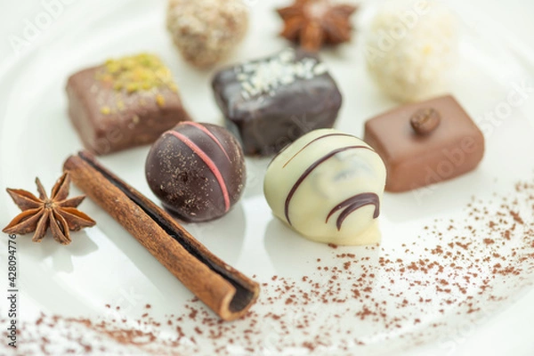 Obraz Chocolates, cinnamon stick and star anise are on a white plate. These are lovely chocolates.