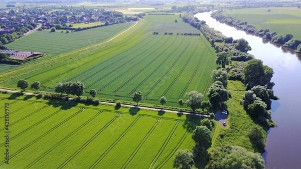 Fototapeta aerial view of farmland with tractor lanes and trees and a river